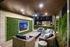 Elegant outdoor lounge area with stylish wicker furniture, modern ceiling fan, and vibrant greenery wall featuring a mounted television. Perfect space for entertaining and relaxation under the night sky.