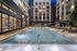 Luxury apartment complex with a stunning outdoor swimming pool, surrounded by elegant lounge chairs and ambient evening lighting.