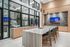 Modern kitchen with sleek marble island, stylish bar stools, and large windows offering natural light and views into a chic living area.