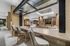 Modern open living space with elegant brick walls, plush seating area, and sleek kitchen featuring pendant lighting. Spacious design ideal for comfort and style.