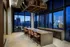 Luxurious urban dining space with a long stone countertop, chic seating, and panoramic city views through large windows.