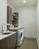 Modern laundry room featuring sleek cabinets, built-in washer and dryer, and elegant countertop with sink.
