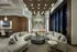 Elegant lobby space featuring plush curved sofas, a modern round coffee table, and striking ceiling lights with a sophisticated marble accent wall.