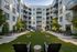 Contemporary apartment courtyard with lush greenery, outdoor seating, and modern building facade.
