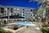 Luxurious apartment complex showcasing a sparkling pool, elegant seating areas, and tall palm trees at night.