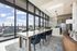 Luxurious open-concept kitchen and dining area featuring floor-to-ceiling windows with stunning views, elegant marble island, and plush seating for a sophisticated urban experience.