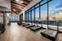 Luxury gym with stunning city views, featuring state-of-the-art treadmills and modern fitness equipment, illuminated by elegant ceiling lights.