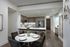 Modern kitchen and dining area featuring sleek countertops, stylish bar stools, and an elegant round dining table set with fine dinnerware.