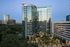 Modern high-rise building with sleek glass exterior and lush green surroundings, showcasing urban sophistication with panoramic city views.