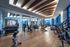 Luxurious modern gym with state-of-the-art equipment, featuring floor-to-ceiling windows and sleek wood flooring, creating an inviting workout atmosphere.