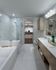 Elegant modern bathroom featuring a luxurious glass shower, marble tiles, and spacious vanity leading to a walk-in closet.