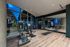 Luxurious fitness center with sleek equipment, mirrored walls, and large windows offering scenic evening views.