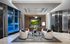 Elegant apartment lobby featuring modern white seating, a central coffee table with floral decor, and large windows for natural light.