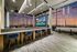 Luxurious apartment lounge with modern bar seating, panoramic city views, and ambient lighting at sunset.