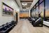 Luxury fitness room with modern exercise equipment, floor-to-ceiling windows, and captivating sunset city views.
