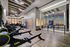 Sleek, modern fitness center with state-of-the-art gym equipment, mirrored walls, and expansive city views at sunset.