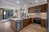 Modern open-concept kitchen with sleek wooden cabinetry, stainless steel appliances, and spacious countertop, seamlessly leading into a chic living area with large windows overlooking city views.