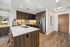 Modern kitchen with stylish dark wood cabinets, stainless steel appliances, and sleek countertops, featuring elegant bar seating and warm lighting.