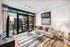 Chic, modern living room with floor-to-ceiling windows offering stunning city views, stylish decor, and a cozy seating area.