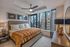 Chic urban bedroom with modern decor, featuring large windows showcasing a stunning city skyline view.