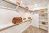Spacious walk-in closet with ample shelving, elegant white finishes, and stylish storage baskets, offering organized luxury.