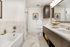Elegant modern bathroom featuring a luxurious bathtub, chic dual-sink vanity, and sleek marble tile flooring.