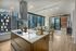Chic open-plan apartment with modern kitchen island, elegant dining area, and floor-to-ceiling windows offering stunning city views.