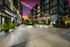 Charming courtyard of a modern apartment complex with string lights glowing against a vibrant sunset sky, surrounded by lush greenery and contemporary architecture.