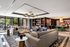 Luxurious living room with modern decor, featuring plush sofas, elegant lighting, and floor-to-ceiling windows opening to a scenic patio.