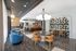 Modern apartment lounge area featuring elegant blue and tan seating, chic lighting fixtures, and stylish geometric wall patterns.