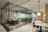 Elegant office space with glass-walled meeting rooms featuring modern decor and cozy seating.