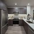 Contemporary kitchen with sleek stainless steel appliances, elegant dark wood cabinets, and a stylish backsplash creating a sophisticated cooking space.