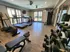 Contemporary fitness center with treadmills, stationary bikes, and weights, featuring large windows and sleek flooring.