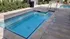 Inviting outdoor pool area with modern tiled borders, surrounded by greenery and seating.