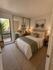 Bright and inviting bedroom with a plush bed, modern decor, mirrored closet doors, and serene outdoor views.