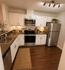 Modern kitchen with sleek stainless steel appliances, white cabinetry, and warm wood flooring, enhanced by stylish decor and ambient lighting.