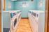 Modern laundry room with multiple washers and dryers against light blue walls.