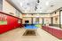 Bright and spacious recreation room featuring a ping pong table, modern seating, and sports-themed decor.