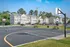 Inviting townhouse complex with adjacent basketball court and picnic area under a clear blue sky.