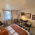 Cozy bedroom with stylish decor, featuring a desk area, patterned armchairs, and wall art.
