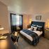 Inviting bedroom with stylish plaid bedding, a work desk, and elegant lighting, creating a cozy atmosphere.