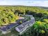Aerial view of charming apartment buildings nestled in lush greenery with ample parking surrounded by scenic woodlands.