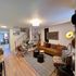 Stylish living room with a brown leather sofa, patterned armchair, and modern decor elements.