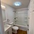 Modern bathroom featuring sleek white fixtures, a full bathtub with chrome accents, and elegant lighting.