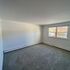 Bright and airy bedroom with large window offering natural light and soft carpet flooring.