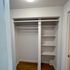 Modern closet space with ample shelving and a hanging rod, featuring sleek white finishes.