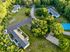 Aerial view of a serene residential community surrounded by lush greenery, featuring multiple apartment buildings, a basketball court, and ample parking.
