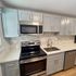 Contemporary kitchen with stainless steel appliances, light gray cabinets, and geometric backsplash.
