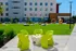 Vibrant outdoor courtyard with modern lime green chairs, lush green lawn, and a chic apartment backdrop.