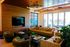 Modern living room with plush seating, stylish ceiling lights, and a large TV, complemented by floor-to-ceiling windows and vibrant decor.
